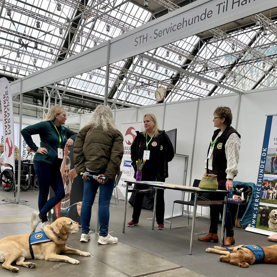 Besøgende snakker med hundetrænere ved STH messestand