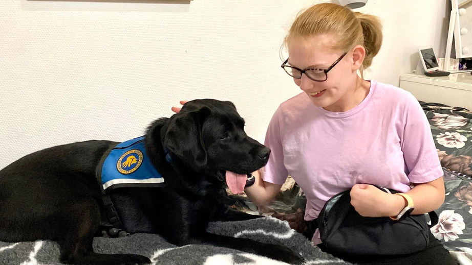 Servicehunden Stella og Marianne der sidder i en seng sammen