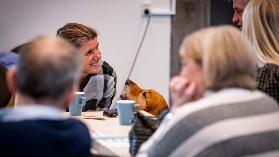 En kvinde der smiler og har hovedet ned til en servicehund der kigger op