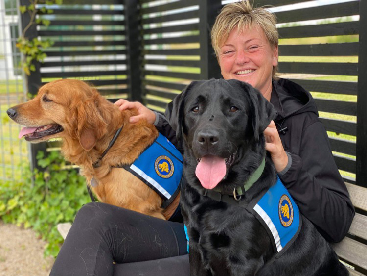 Instruktør Anette sidder sammen med to servicehund