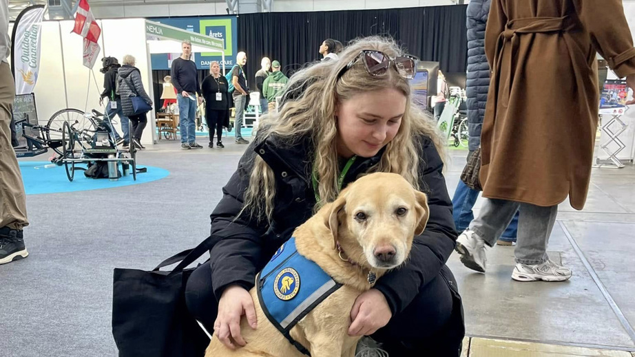 Servicehund sammen med en besøgende på STHs messestand