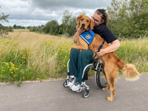 Servicehund Forza og bruger Camilla udenfor foran en mark
