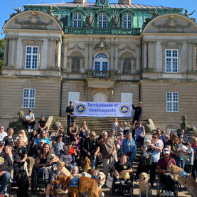 Fællesbillede med en flot bygning bagved til Dog A Thon