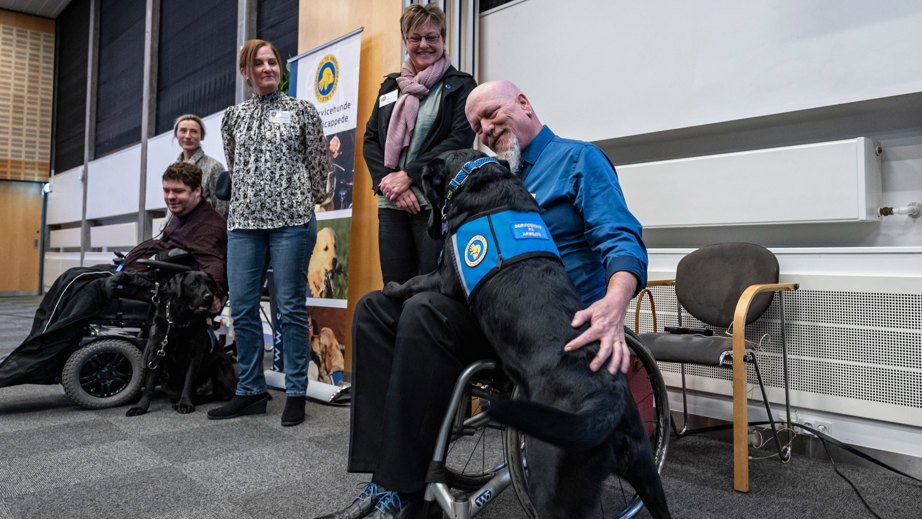 Servicehunden Dallas står op af bruger Jan til graduation