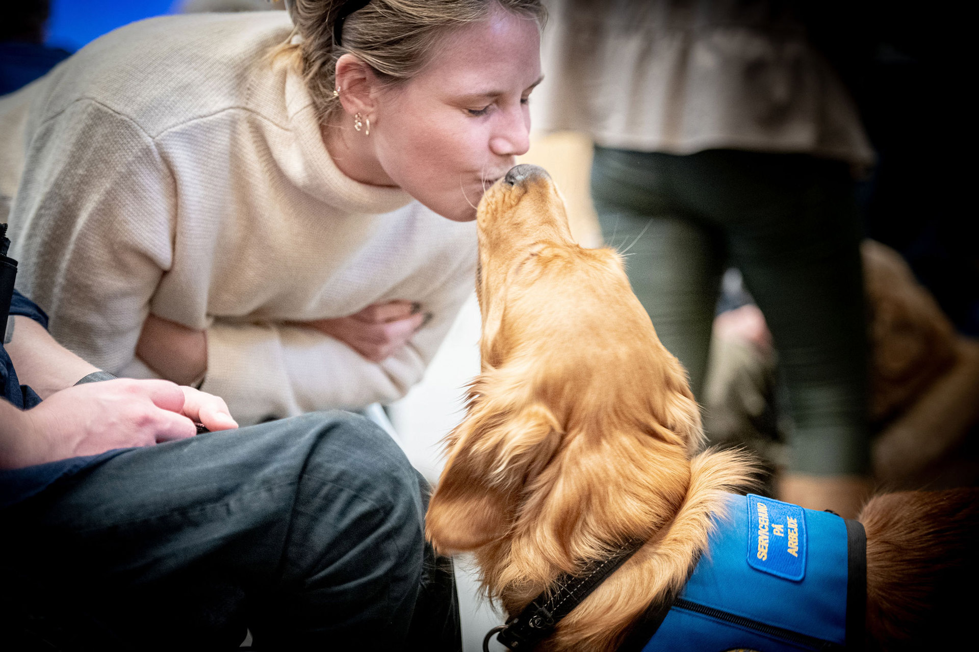 En kvinde der kysser en servicehund til graduation