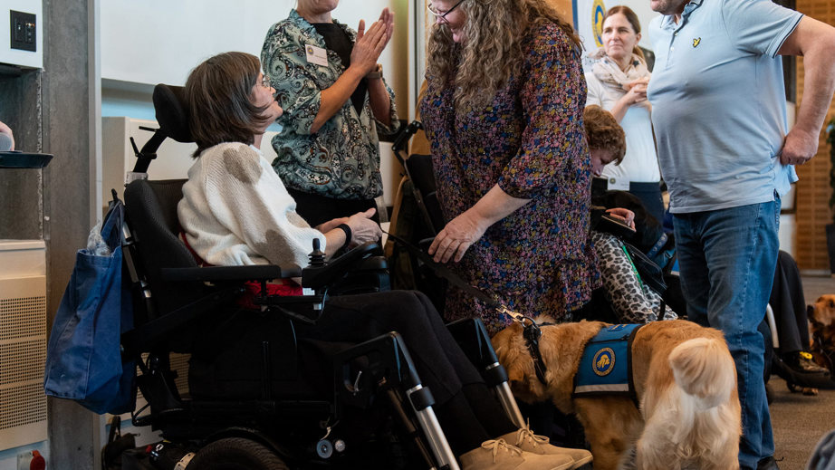 Værtsfamilie af servicehund giver hånd til bruger til graduation