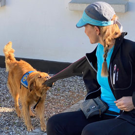 Servicehunden Forza til hundetræning og tager jakken af en hundetræner