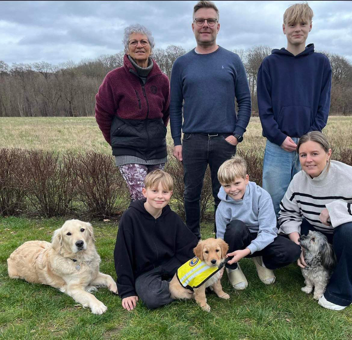 Hvalpeaspirant Daisy Ii på et fællesbillede med hvalpevært og familien