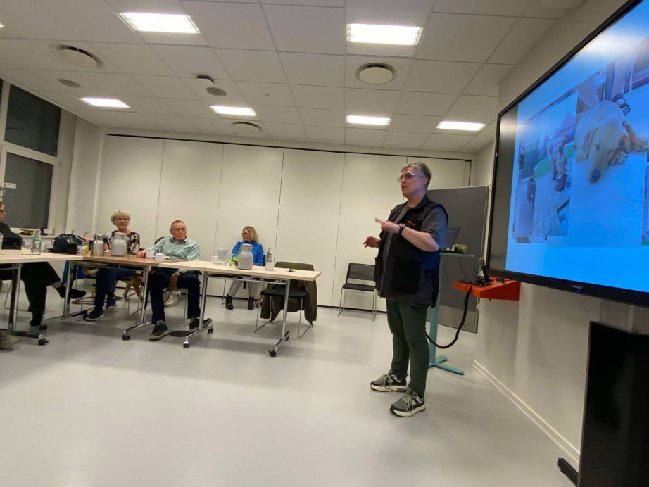 Informationsmøde hos STH hvor en dame snakker foran en stor skærm